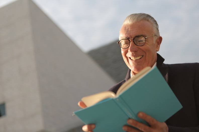 Een oudere man met een bril kijkt in een boek